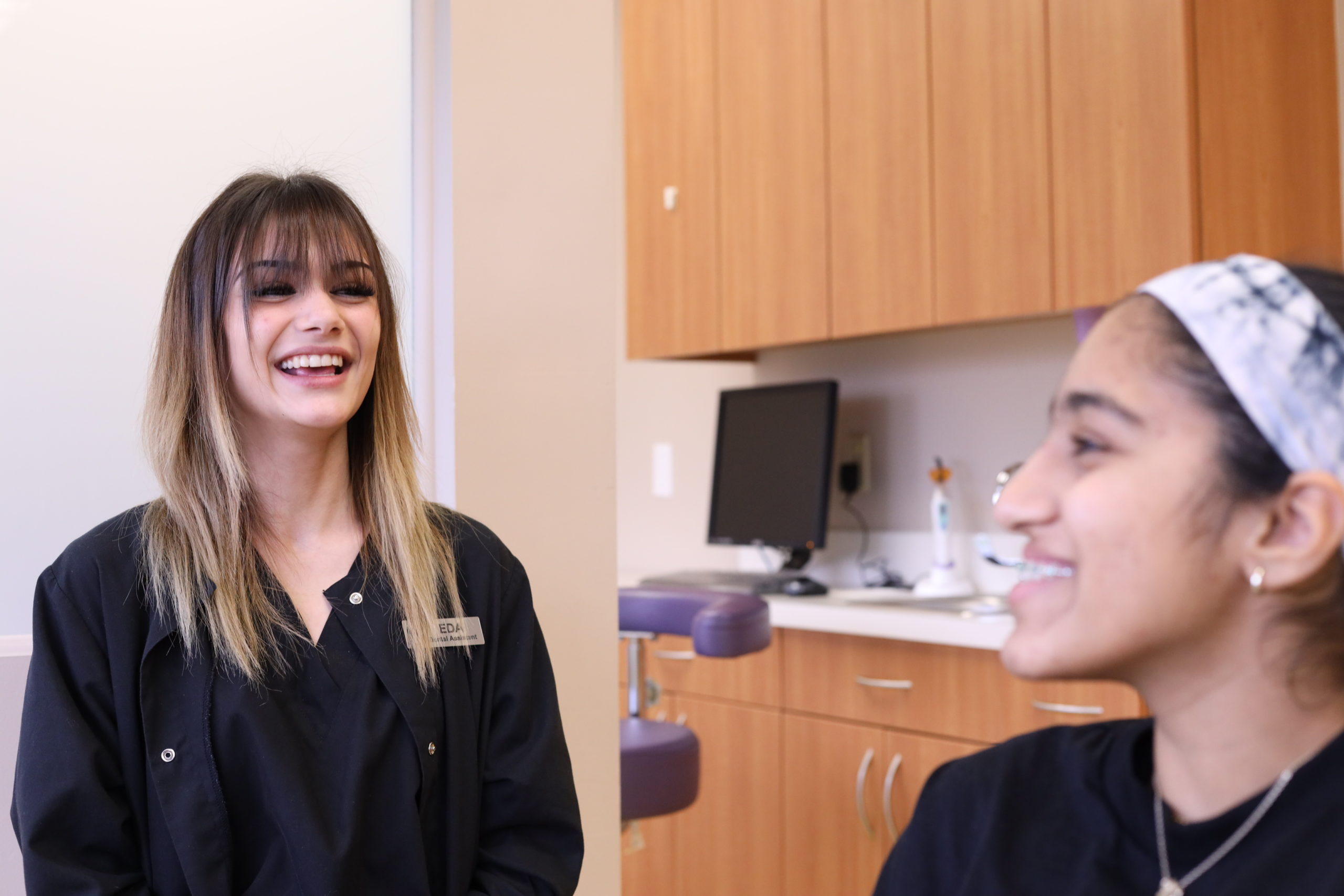 Smiling team member laughing with a patient in the treatment area at Monroe Orthodontics, the Monroe Township orthodontics practice of Dr. Susan Leiva